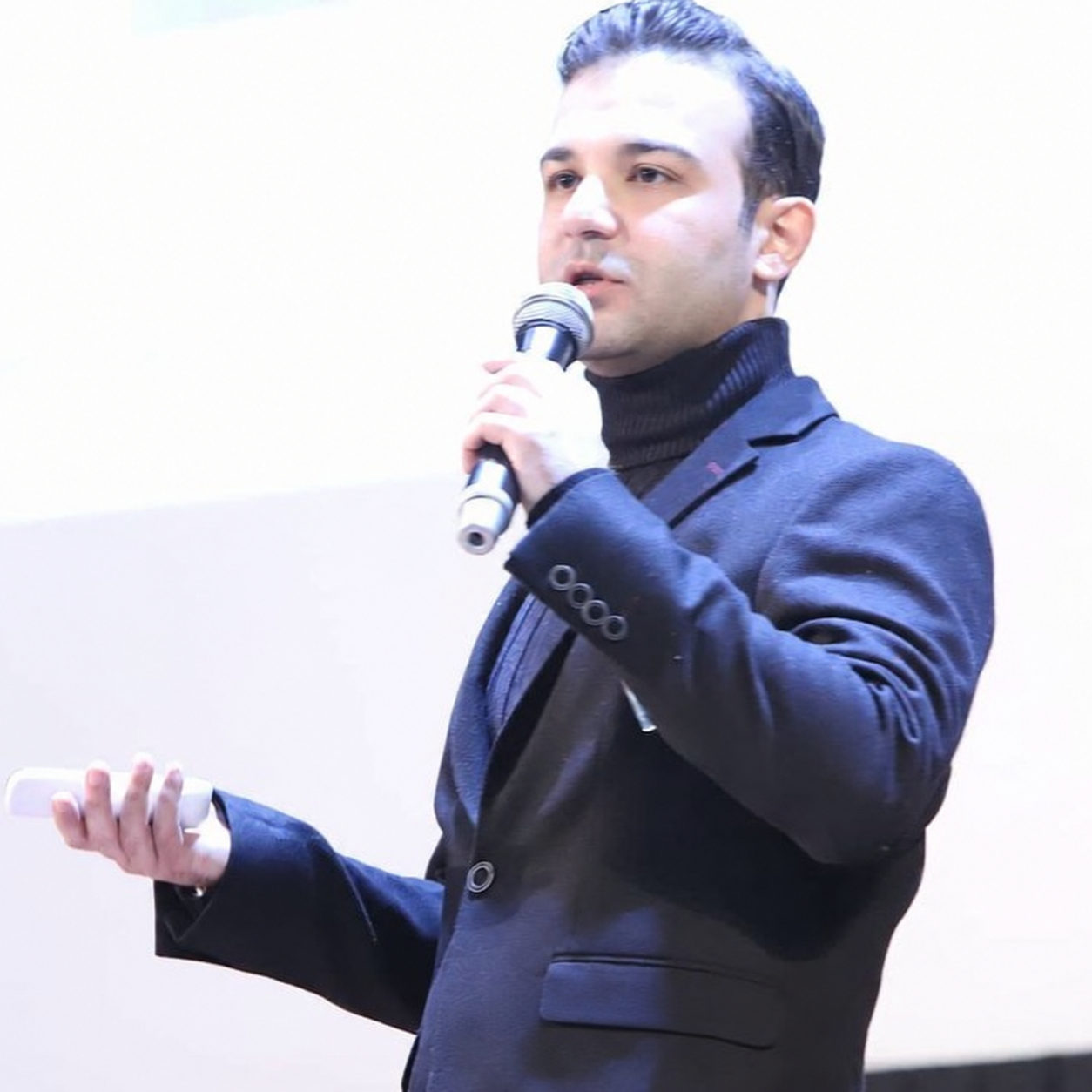 Mojtaba Tabatabaie speaking into a microphone at an event